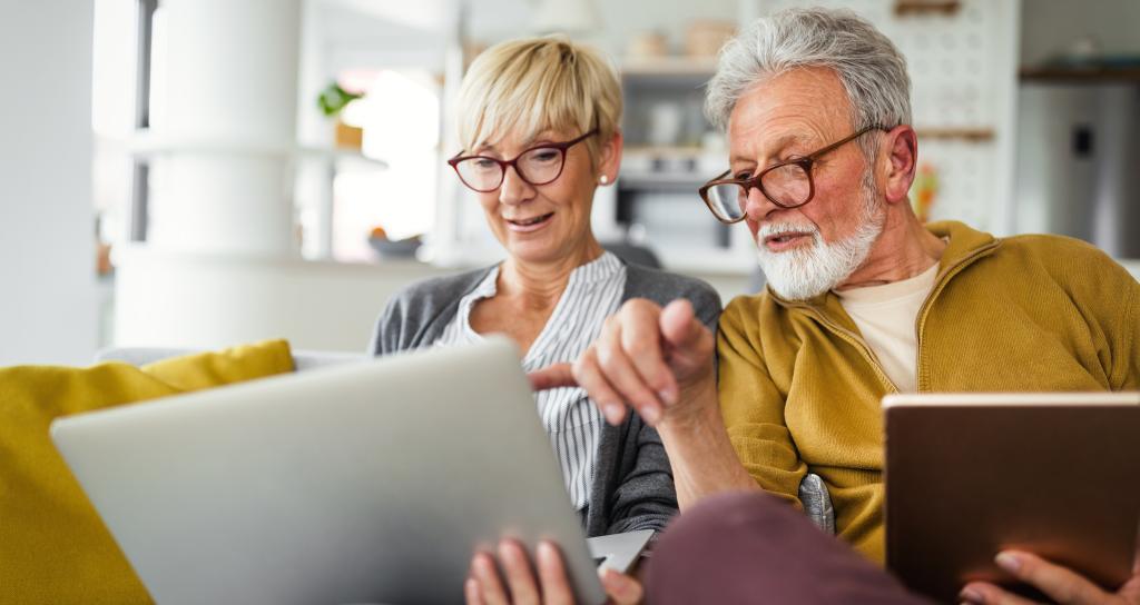 Couple at home on sofa with laptop and tablet